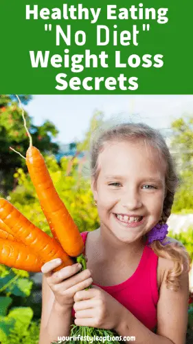 Young girl holding carrots in the garden.